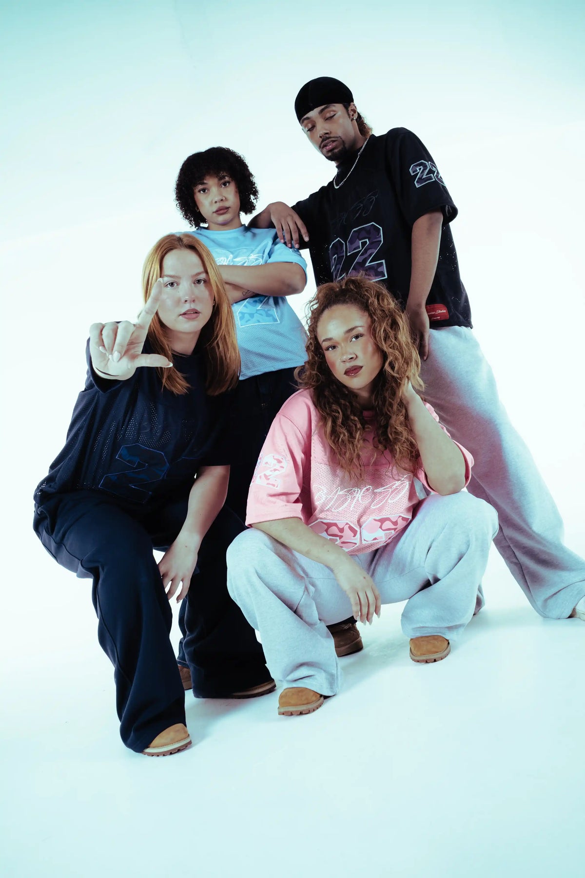 Four models wearing BASICSS 22 Camo Jerseys in navy, light blue, black and pink, featuring oversized streetwear fits and bold camouflage number graphics in a minimalist studio.