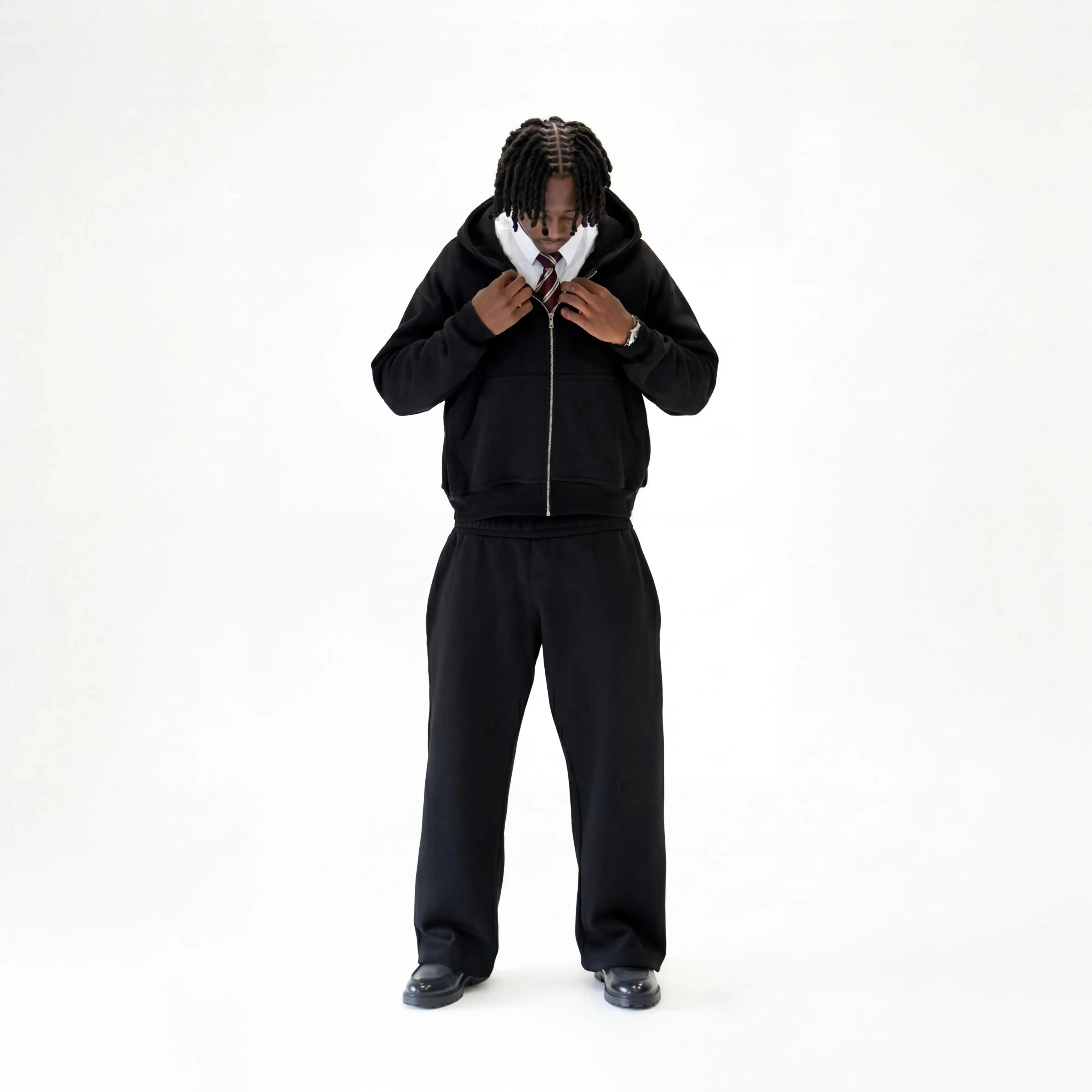 Model wearing premium black tracksuit on a white studio background. 