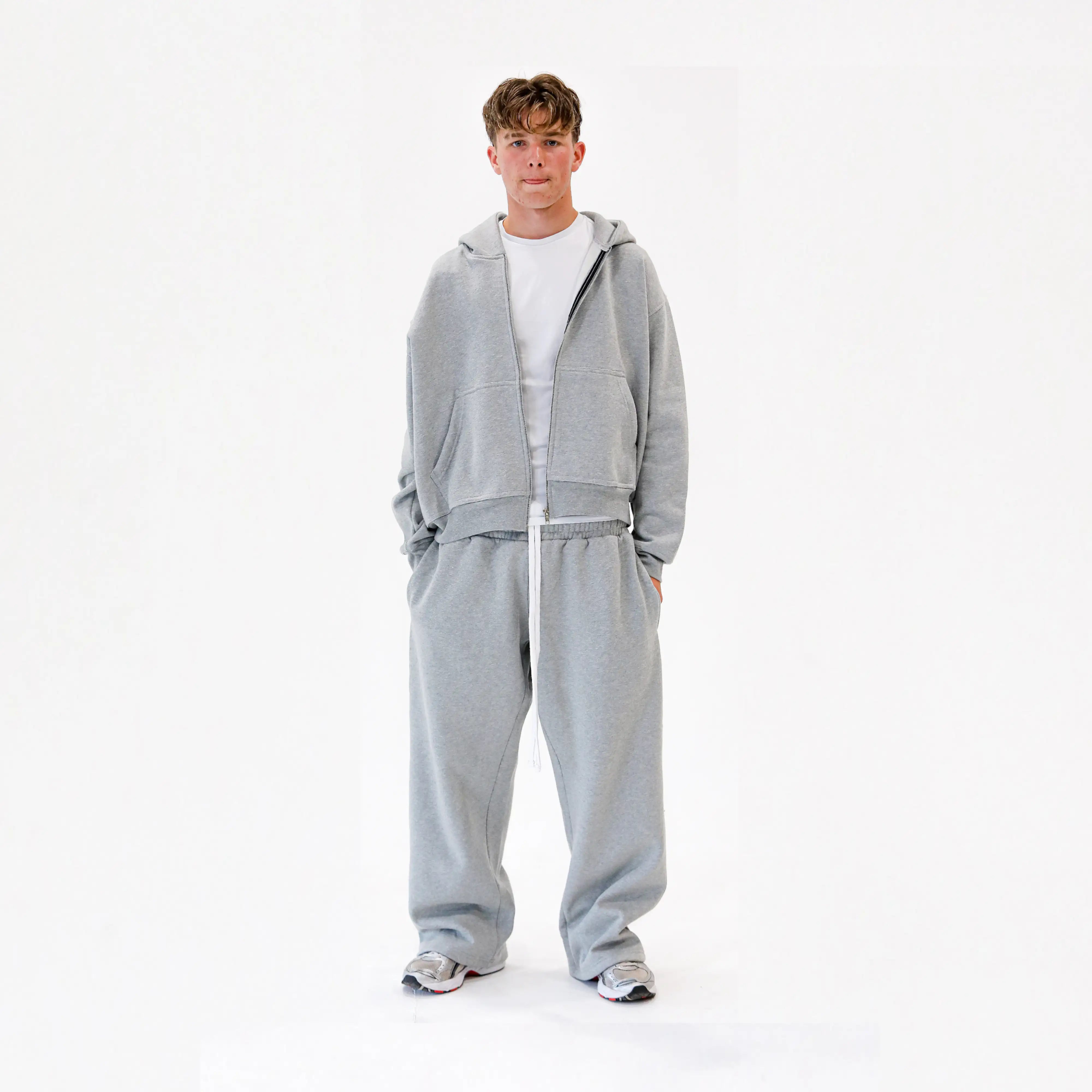 Male wearing grey tracksuit and white slim fit t-shirt on a white studio background 